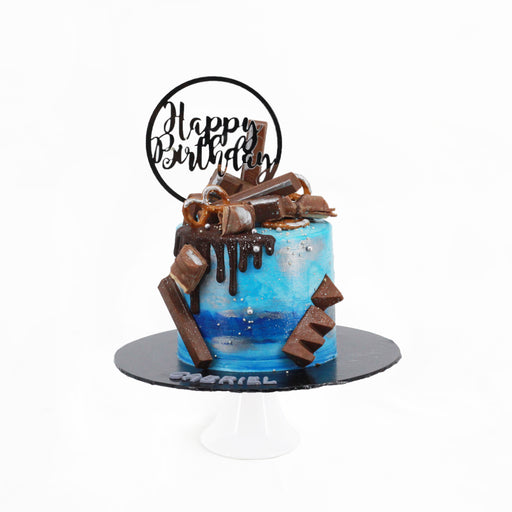 Cake frosted with blue buttercream, topped with chocolatey treats of Toblerone, Kit Kats and Kinder Bueno