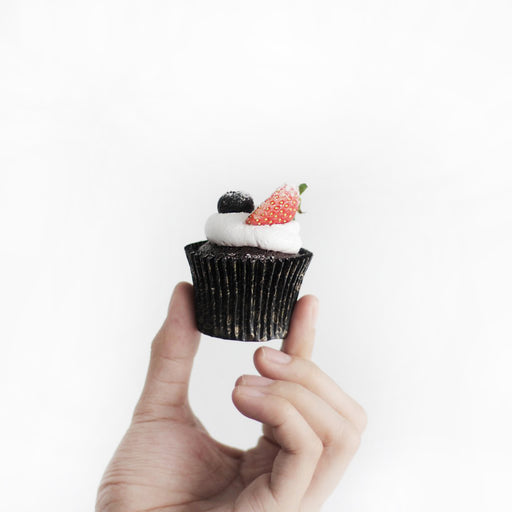 Chocolate cupcakes with berries filling, topped with whipping cream, strawberries and blueberries