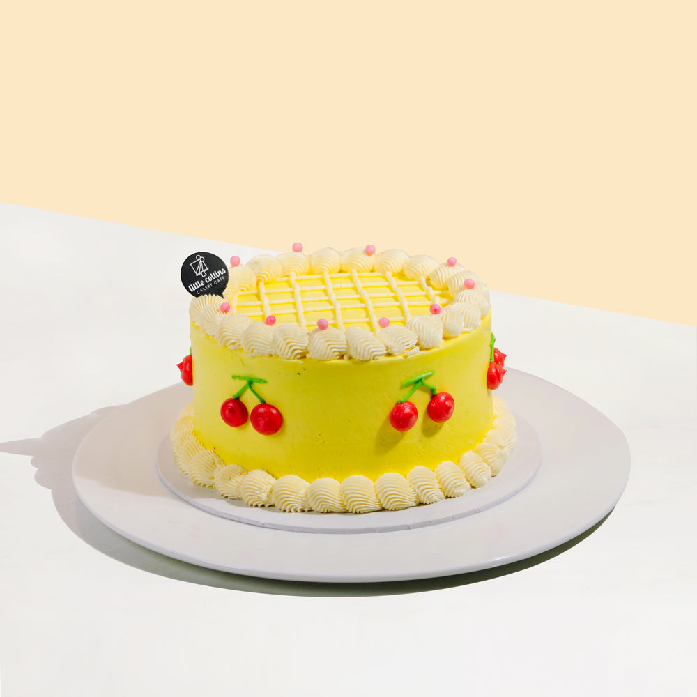 Yellow cake decorated with cream swirls and cream piped cherries