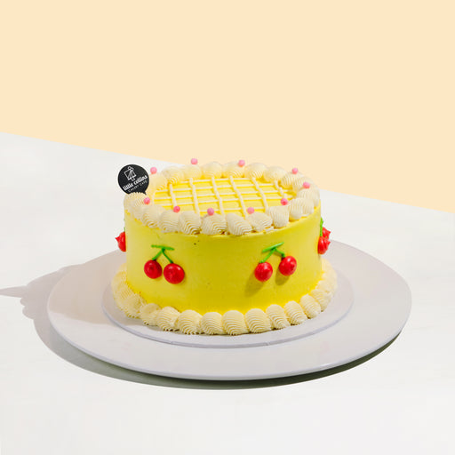Yellow cake decorated with cream swirls and cream piped cherries
