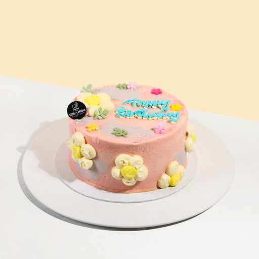 Pink buttercream cake with purple hints, decorated with hand piped daisies