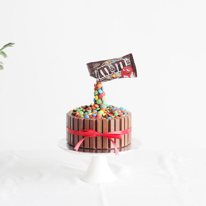 Butter cake with a fence of KitKat, topped with m&ms and an anti-gravity packet
