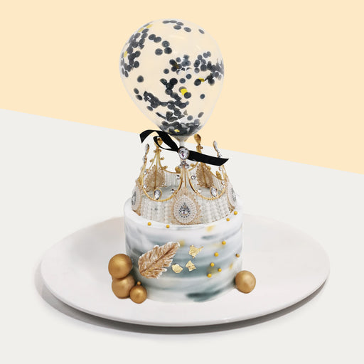 Grey gradient buttercream cake with gold decorations, a crown and confetti balloon