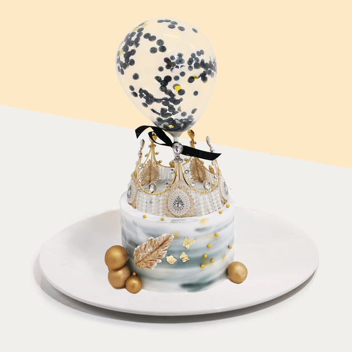 Grey gradient buttercream cake with gold decorations, a crown and confetti balloon