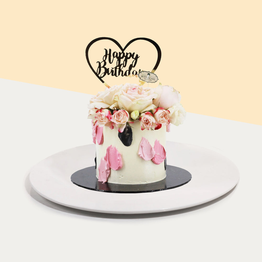 Buttercream cake with pink paint strokes, topped with fresh flowers