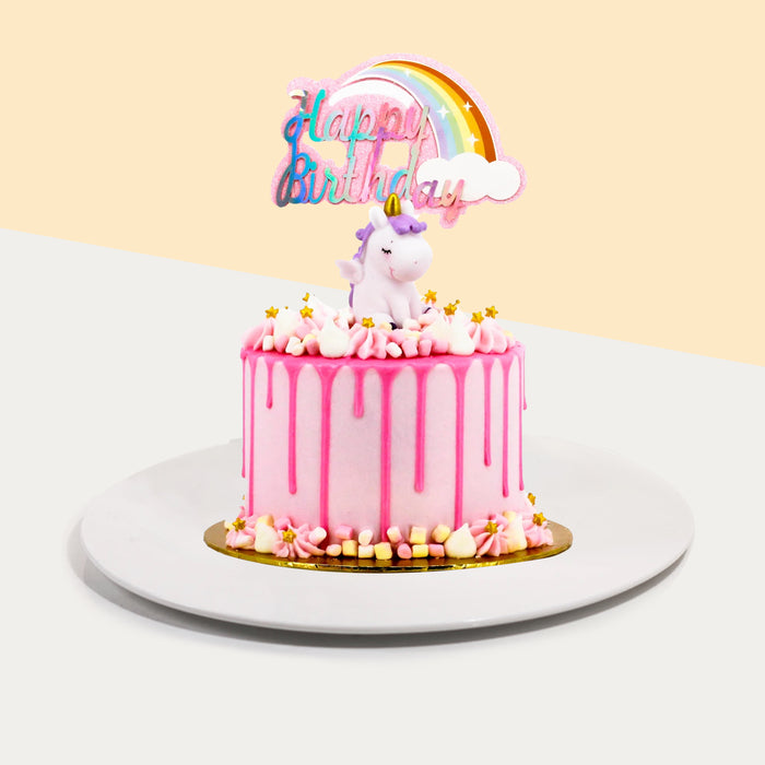 Pink buttercream frosted cake, with pink chocolate drizzle and a unicorn figurine on top