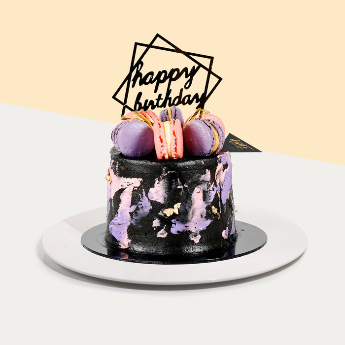 Chocolate cake with salted caramel buttercream, purple and pink strokes, and macarons on top