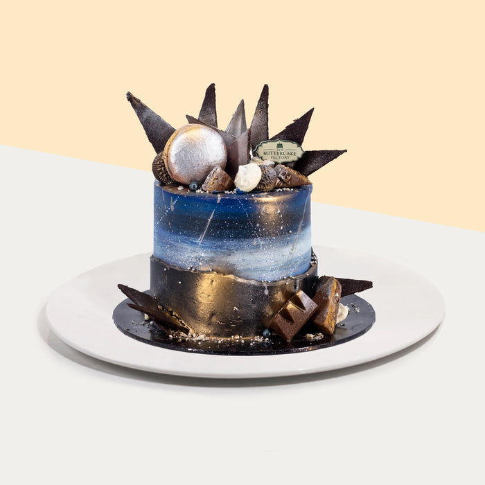 Buttercream cake with fault line design, painted to look like the galaxy, with chocolate treats on top