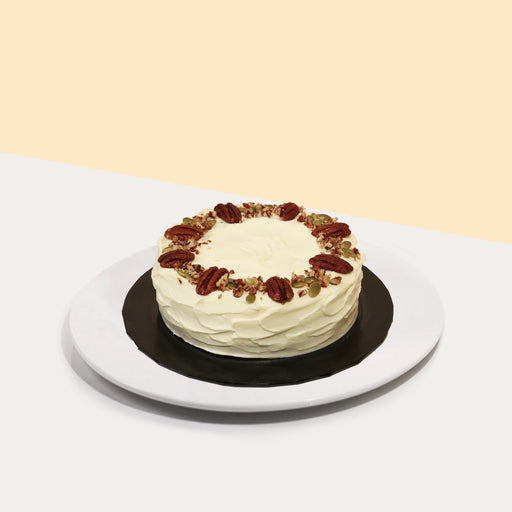 Pumpkin cake with cinnamon cream cheese frosting, topped with pumpkin seeds and nuts