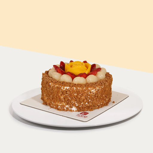 Vanilla sponge cake with lychee filling, coated with cream and Lotus Biscoff crumbs