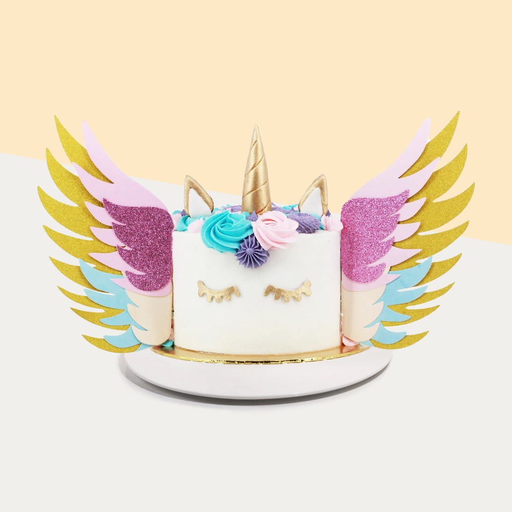 Unicorn cake with colorful buttercream spirals, and paper wings with multi-coloured paper