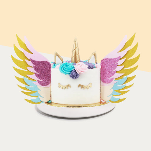 Unicorn cake with colorful buttercream spirals, and paper wings with multi-coloured paper