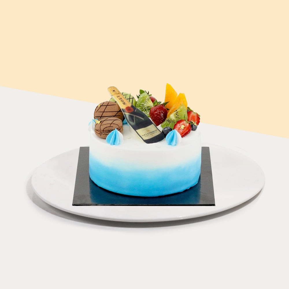 Blue and white cream frosted cake, with mango fillings, topped with macarons and fresh fruits