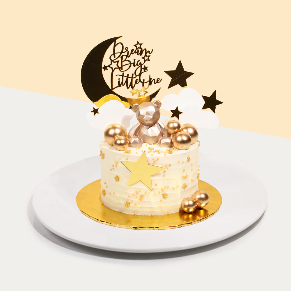 White buttercream cake decorated with golden spheres, geometric bear and 2d printed stars