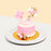 Pink and white buttercream cake, with a girl riding a train cake topper