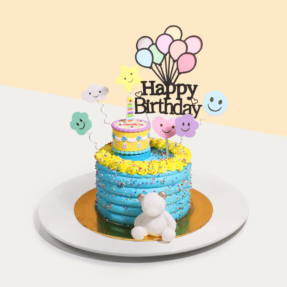 Blue buttercream cake with colorful sprinkles, and a mini cake on top