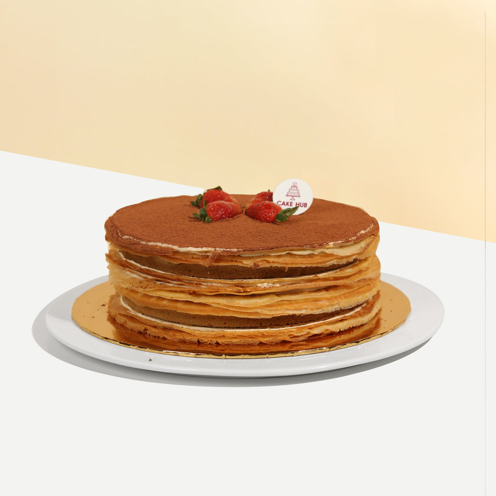 Crepe cake with Italian Tiramisu sponge layers, topped with cocoa powder and strawberries