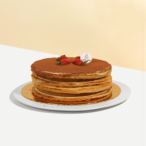 Crepe cake with Italian Tiramisu sponge layers, topped with cocoa powder and strawberries