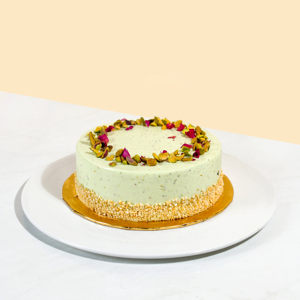 Vanilla sponge cake with pistachio cream and milk chocolate ganache, topped with chopped pistachios and dried rose petals