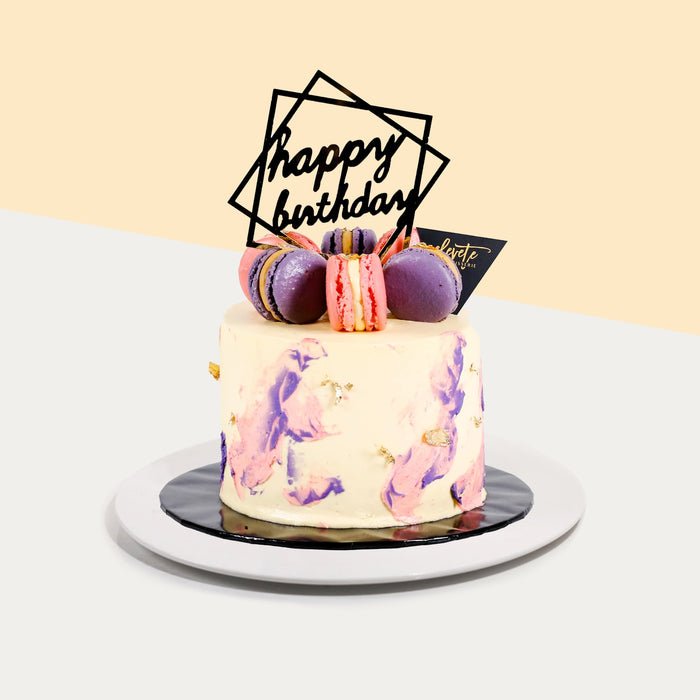 Butter cake frosted in pastel coloured buttercream and edible gold leaf, topped with macarons
