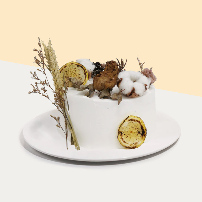 Rustic cake with dried foliage, flowers, cotton, and burnt lemon slices decorations